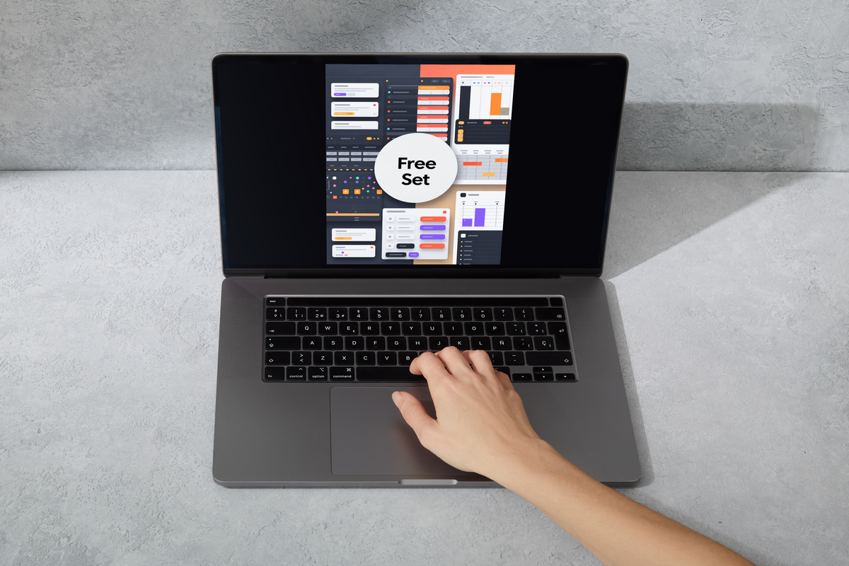 A gray laptop sits open on a light gray textured surface, with a hand resting on the trackpad. The screen displays a dark dashboard interface with a white circle reading 'Free Set'.